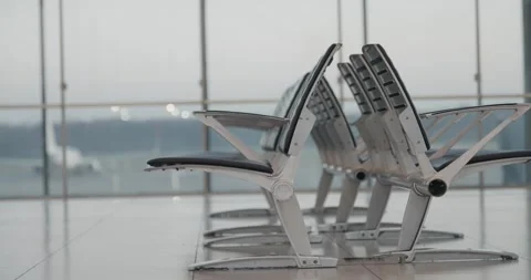 A row of empty lined chairs in front of a window at airport, establishing sho Stock Footage 335425216