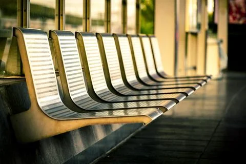 Row of empty metal seats or waiting bench at a train station platform, bath.. Stock Photos