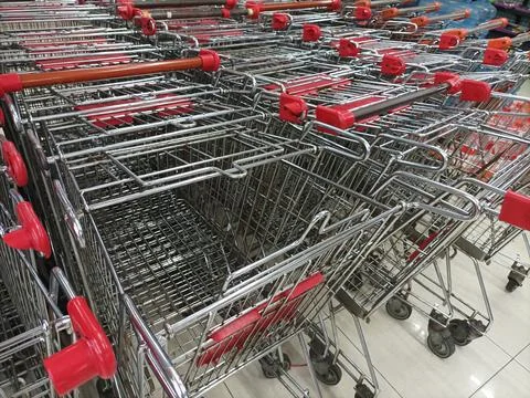 Row of empty metal shopping carts with red handles in a supermarket store. Stock Photos