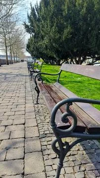 Row of empty park benches on a cobblestone path Foto stock