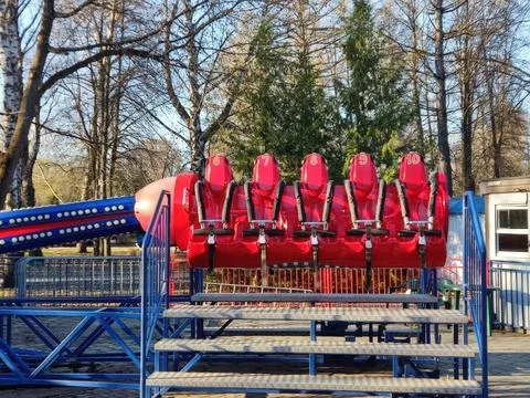Row of empty red amusement park ride chairs on a sunny day Foto stock