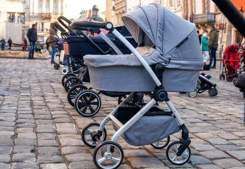 Row of empty stroll prams parked on city street paving stone Stock Photos