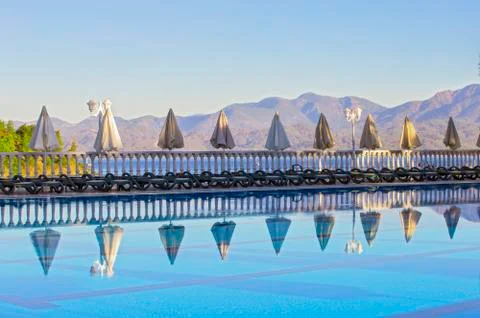 Row of empty sunbeds by the pool and the sea in the morning at dawn. Comforta Stock Photos