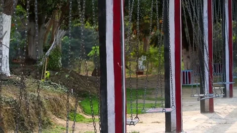 Row of empty swings in park with trees and greenery Stock-Footage 332611706