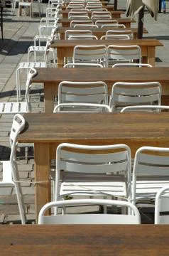 Row of empty tables and chairs at restaurant on the street Stock Photos
