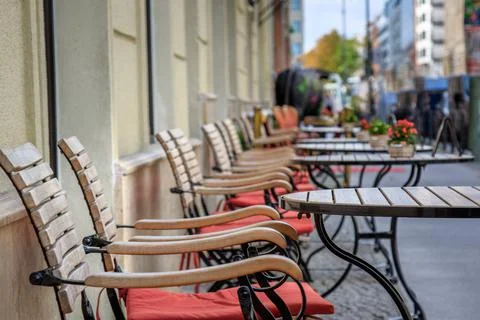 Row of empty tables and chairs on a sidewalk in Berlin, Germany. Stock Photos