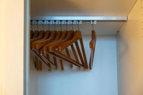 A row of empty wooden hangers inside a wardrobe. Stock Photos