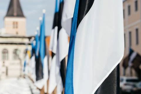 A row of Estonian flags waves in the winter sun, decorating a historic Stock Photos