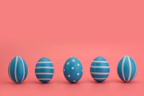 A row of five blue decorated Easter eggs on a pink background. Photos