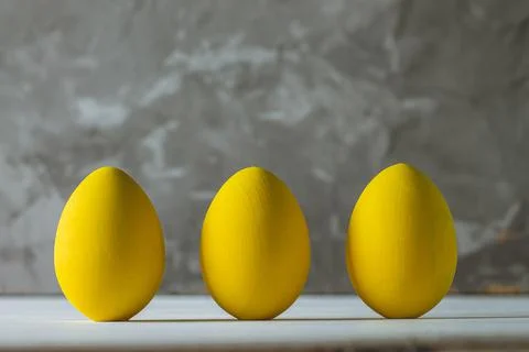 Row of five bright yellow Easter eggs, standing on white wooden surface on gr Foto stock