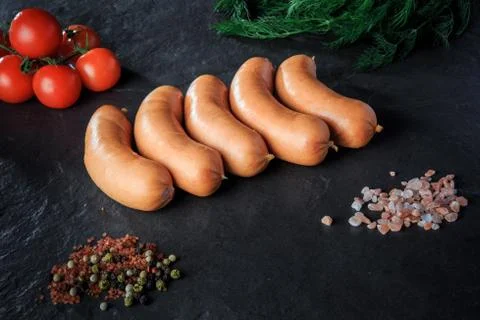 Row of five raw short thick sausages with dill and tomatoes Stock Photos