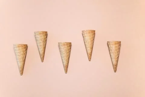 A row of five small ice-cream cones on a beige background Stock Photos