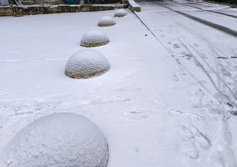 A row of five snow-covered stone fences, footprints marking the path. Winte.. Stock Photos