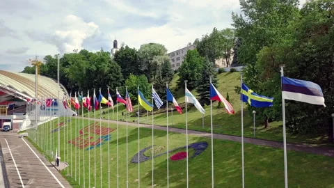 A row of flags of different countries on flagpoles waving in the wind against a Video stock 138510902