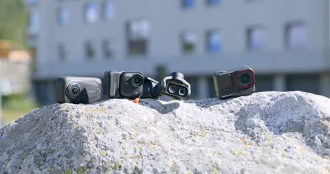 Row of Four Action Cameras Displayed on Rock Outdoors Vidéo 348775230