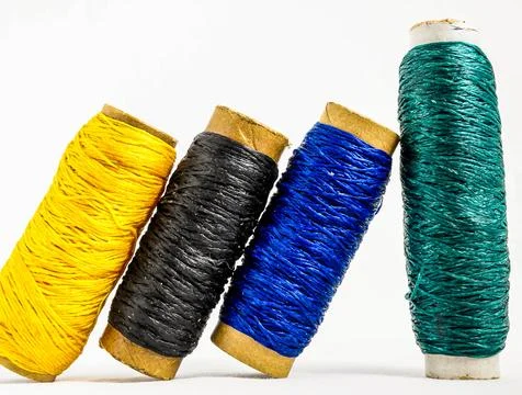 A row of four different colored threads are laid out on a white background Stock-Fotos