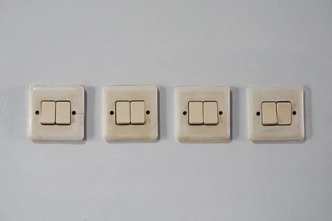 Row of four old double light switches on a white wall for home electrical c.. Stock Photos