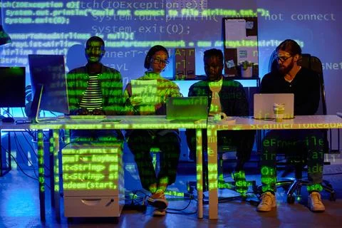 Row of four young diversity programmers sitting by desk in front of laptops Stockfoto's