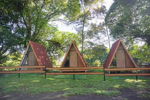 Row of A-frame triangular cabins surrounded by lush green forest, perfect Fotos de archivo