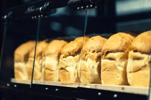 Row of fresh bread loafs lying on the shelf in bakery Stock Photos