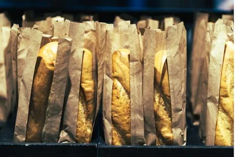 Row of fresh bread loafs staying on the shelf in bakery Stock Photos