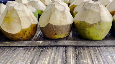 Row of freshly trimmed young coconuts on rustic wooden table Stock Footage 346742810