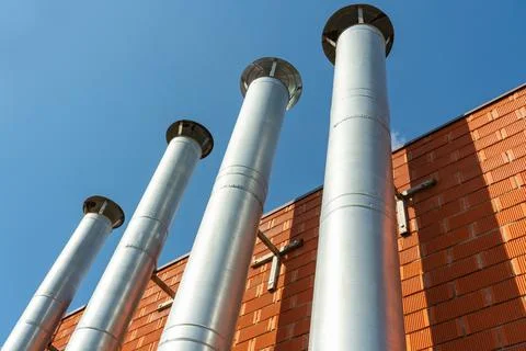 A row of galvanized chimneys on the facade of a red brick building Stock Photos