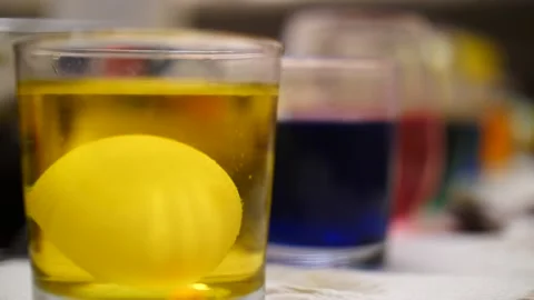 Row of glasses full of dye and Easter eggs pulling focus Stock Footage 151503846