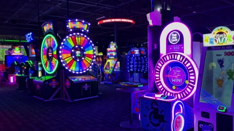 Row of glowing neon ticket redemption wheel and puzzle arcade machines inDave-20 Stock Footage 339490539