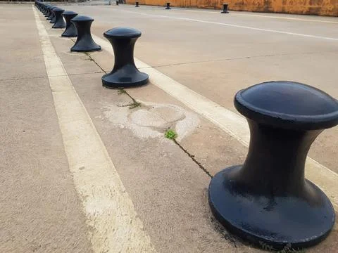 Row of heavy black docking bollards positioned along the edge of an industria Stock Photos