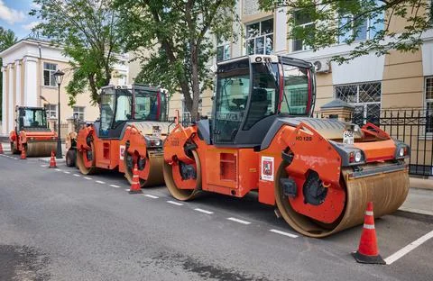Row of heavy vibratory rollers in the city street ready for asphalt paving, c Stock Photos