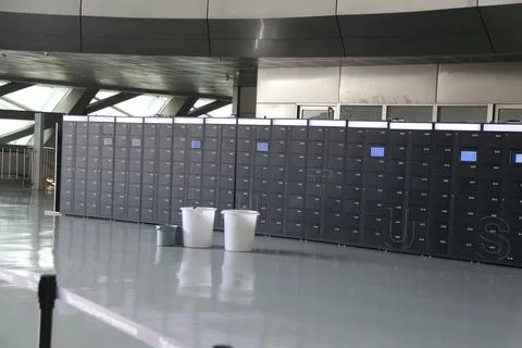 A row of high-tech electronic lockers with white plastic trash cans placed .. Stock Photos