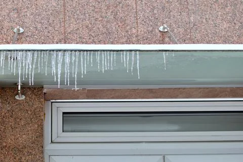 Row of icicles of different sizes hanging from canopy Stock Photos