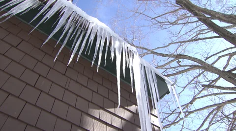 A Row of Icicles Melting Against a Brown House Stock Footage 35362684