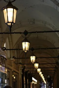 Row of illuminated lanterns lining urban tunnel archway at night Stock Photos