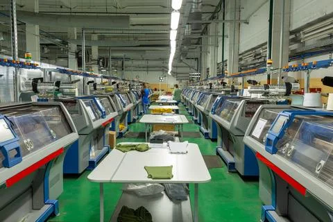 A row of industrial textil flat knitting machines in a knitwear factory. Stock Photos