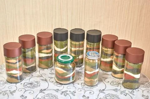 A row of jars filled with a set of bright home-made spices Stock Photos