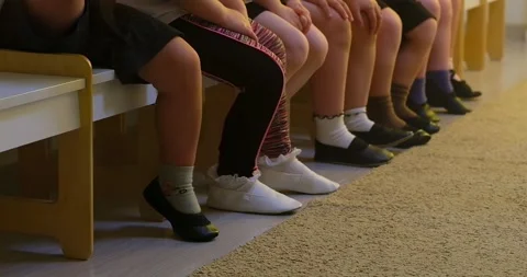 Row of kids sitting on chairs in a classroom. Group of child legs and feet .. Stock Footage 333564128