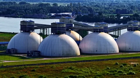 A row of large dome-shaped industrial storage units stands beside a riverside Stock Footage 325057518