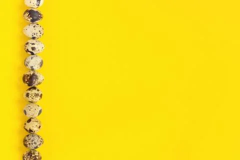Row on left edge quail eggs on yellow paper background. Easter concept. Templ Stock Photos