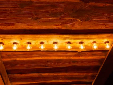 Row of lightbulbs on rustic wooden ceiling Stock Photos