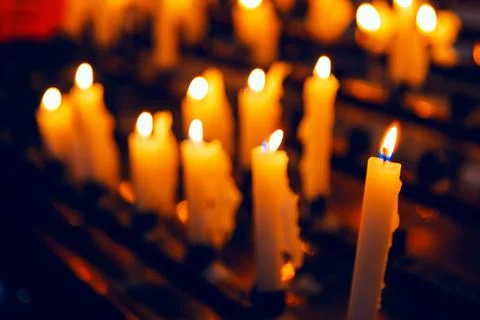 Row of lit candles casting a warm glow Stock Photos