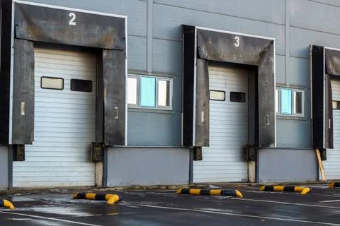 Row of loading docks with shutter doors at a warehouse. Warehouse logistics Stock Photos