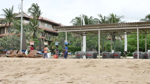 Row of local people with baskets on their heads walking on the beach in Nusa Dua Stock Footage 178478486