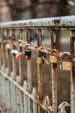 A row of love locks attached to a rusty metal fence, symbolizing romance Stock Photos