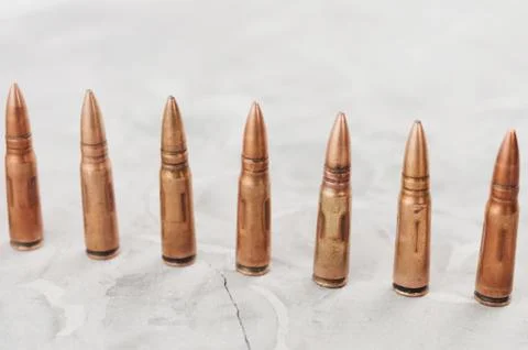 Row of many metal bullets on grey broken concrete Stock Photos
