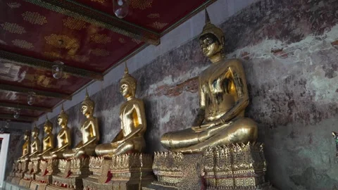 A row of many statues of a gold Buddha sitting in a meditative pose in the Stock Footage 289800221