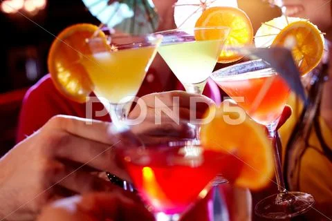 Row of martini glasses with cocktails in hands of people Stock Photos