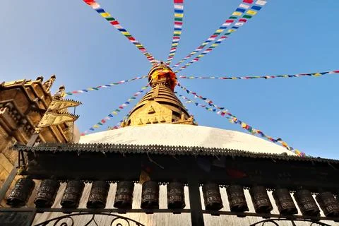 A row of metal prayer wheels in front of the Swayambhunath Stupa, Temple, K.. Stock Photos