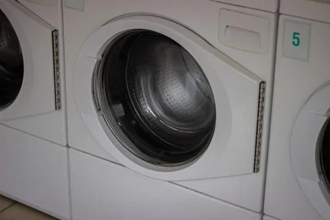 Row of modern front loading washing machines in laundromat Stock Photos